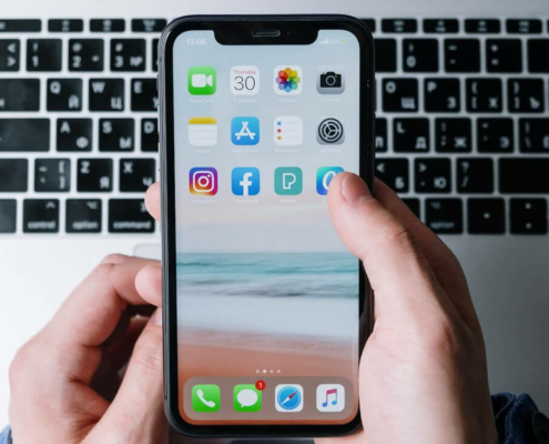 Updated: When To Post On Social Media 3 hand holding iphone tapping on social app